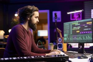 Songwriter taking notes to create new music in his home studio, writing down lyrics and harmonic elements before recording his song on daw software, acoustical engineering post production. photo