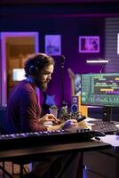 Sound engineer editing audio recordings with daw software and mixing console, adjusting volume levels on amplifier. Artist mixing and mastering soundtracks, operating pre amp knobs. photo