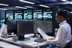 Engineer in data center doing yearly maintenance checkup to prolong hardware life span, looking over documents, monitoring server infrastructure and reading specifications paperwork photo