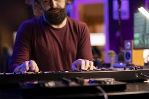 Audio engineer pressing keys of electric synthesizer and composing new song, adjusting volume level. Singer composer producing music on electronic piano midi controller, mixing console. photo