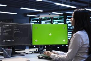Engineer in server hub using green screen PC to repair equipment storing datasets. Professional using mockup computer to do debugging on rigs doing computational operations photo