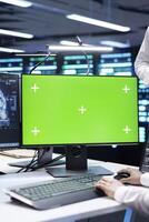 Close up of computer scientist monitoring server hub using AI software on green screen PC. Supervisor using mockup device to oversee neural network high tech facility used for machine learning photo