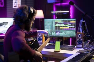 Beginner artist learning strings accords to play guitar by watching tutorials and online lessons, smartphone shows greenscreen mockup. Singer practicing acoustic instrument skills in home studio. photo