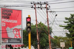 Traffic lights at urban intersection with electricity poles and advertising billboards in the background photo