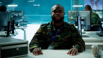 Reconnaissance expert engages in a online videocall in a high tech control room, coordinating intelligence and surveillance efforts with remote teams to enhance national defense program. Camera A. photo