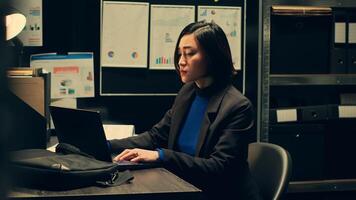Private investigator comparing sources to confirm case details or cross check confidential information, compiling statistical data on crime trends. Asian federal agent in incident room. Camera A. photo