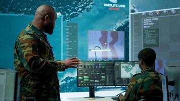 Military staff work in a high tech monitoring room command post, managing cybersecurity operations and surveillance systems. Soldier ensures data protection for national safety. Camera A. photo