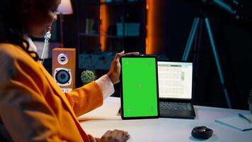 African american girl holding tablet with greenscreen layout, conducting data analysis for financial or economics courses. Student uses isolated mockup display on device, work from home. Camera B. photo