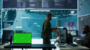 Military IT specialist in command center working on collecting field data, process real time surveillance footage and imagery for successful defense operation. Isolated mockup display on pc. Camera B. photo