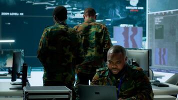 In a high tech military office, soldiers team analyze real time data collected by surveillance system. Staff interpret intelligence and coordinate operations to ensure national defense. Camera A. photo