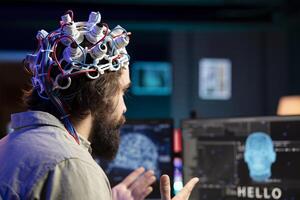 Software developer using EEG headset device translating thoughts into PC commands using brainwave signals. IT professional controlling computer functions using mind, helped by technology, close up photo