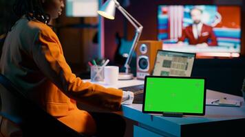 African american pupil looks at greenscreen display on tablet, learning to calculate cost and opportunity. Young woman working on financial software for economics classes. Camera A. photo