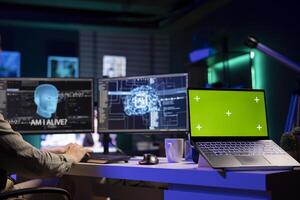 Green screen laptop next to man talking with AI becoming sentient and asking questions. Mockup notebook and developer chatting with artificial intelligence wishing to befriend humanity photo