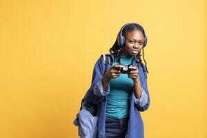 Portrait of cheerful woman playing videogames, holding controller, isolated over studio background. Gamer smiling, having fun by participating in PvP online multiplayer game using console system photo