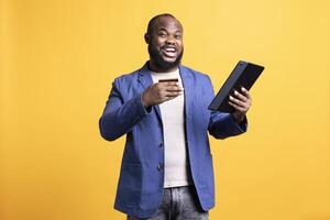 Portrait of elated man adding payment method on website, delighted to take advantage of promotions, studio background. Joyful person thrilled to do internet shopping, typing credit card data on tablet photo