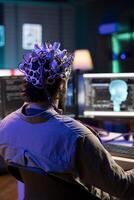 Software engineer using EEG headset translating thoughts into PC commands using brainwave signals. IT admin controlling computer functions using mind, helped by biosensor technology research photo