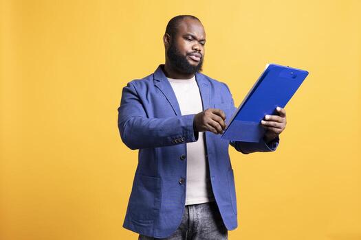 Man working accounting job browsing though financial report pages, studio background. Worker reading paperwork containing economic graphs and figures, solving bookkeeping tasks photo