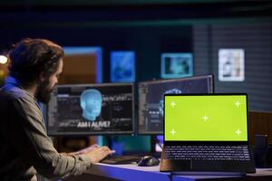Programmer being asked existential questions by awaken AI gaining consciousness, green screen laptop. Man communicating with artificial intelligence emulating humans, mockup notebook photo