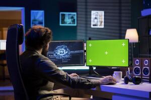 Computer scientist updating artificial intelligence machine learning algorithm on green screen PC. IT specialist in apartment office uses programming to upgrade AI on mockup monitor photo