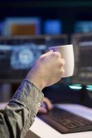Man drinking coffee and updating artificial intelligence neural networks, writing binary code script. IT professional upgrading high tech AI, enjoying hot beverage, close up photo