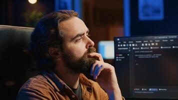 Software technician puzzled in front of computer screen while writing complex code, thinking of solution. IT expert feeling confused while trying to solve database bugs, camera A close up photo