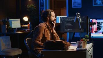 Freelancing system administrator arriving in personal office at home, resuming work on coding. IT expert starting job in apartment, writing lines of code on computer, camera A photo
