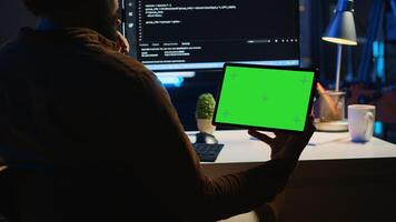 Software developer watching programming tutorial on isolated screen tablet in home office. Man holding chroma key portable device to learn coding from internet guide photo