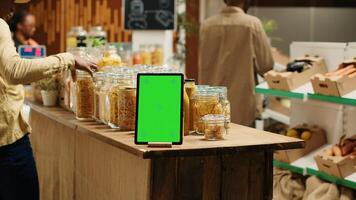 Greenscreen layout on tablet at local organic supermarket, ethically sourced products for sustainable lifestyle. Device running isolated mockup template or chromakey in zero waste eco store. Camera 1. photo