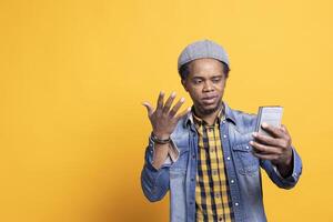 African american carefree guy checks his smartphone notifications on camera, browsing online webpages and social media apps. Confident casual person talks to his friends using internet connection. photo