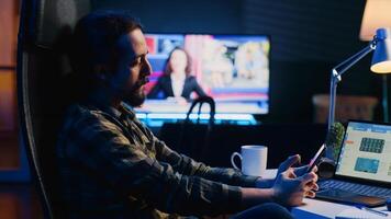 Man taking break from checking financial graphs on laptop, playing games on phone. Remote worker relaxing after analyzing business graphic figures, enjoying videogame on smartphone, camera A photo