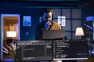 Man working from home developing software in Java programming language using laptop. Programmer walking through apartment thinking how to solve coding problems using notebook photo