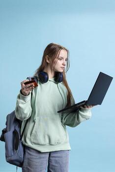 Teenager adding payment method on website using laptop, taking advantage of promotions studio backdrop. Person doing purchases online, typing debit card details on notebook photo