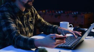 Upbeat man spending money while doing online shopping, typing debit card information on laptop. Freelancer adding payment method on website, feeling enthusiastic about purchasing, camera A close up photo