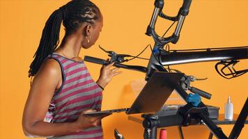 Engineer doing bike servicing in studio background repair shop, searching replacement components online on laptop. Professional looking for necessary work tools for repairing bicycle photo