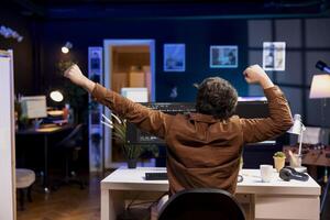 Fatigued cybersecurity expert stretching after looking for company security vulnerabilities and preventing malware infections all day. Developer relaxing muscles while installing fortified code photo