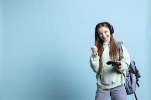 Euphoric woman playing intense gaming console game, celebrating win, isolated over studio background. Ecstatic young girl using controller, excited after being victorious in videogame photo