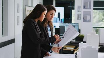 Creative engineers sketching blueprints on paper, working to design floor plan layout for new apartment project. Team of employees developing schemes and drafts in small business office. photo