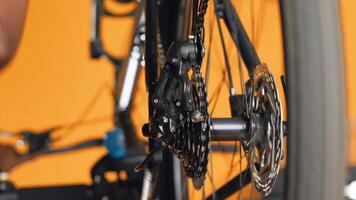 Close up shot of bicycle wheel mechanism being examined by woman during performance assessment. Focus on bike components tested by professional in blurry background ensuring proper function photo