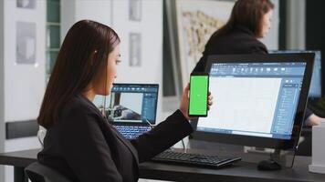 Engineer showing phone with greenscreen template on display, working at a architectural agency office. CAD expert using isolated chromakey layout on copyspace screen, mockup concept. photo