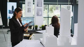 Architect working with project blueprint and cad software, taking measurements with 3d building model in coworking space. Architecture agency employee looking at engineering draft. photo
