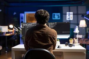 IT specialist working from home developing software in JavaScript programming language using PC. System engineer in apartment writing lines of code on computer using keyboard photo