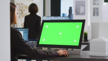 Cad specialist using computer with greenscreen at office desk, reviewing pc display with isolated copyspace layout in unicorn business coworking space. Architect blank chromakey template on monitor. photo