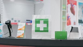 Paper bag with medicine and greenscreen surface shown on pills box at checkout counter, empty pharmacy having medicaments and vitamins at cash register. Nutrients and chromakey copyspace layout. photo