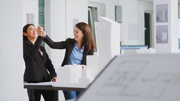 Architects doing high five gesture after finishing blueprints, feeling happy about translating measurements and determining scale elements for building development. Women solve task successfully. photo