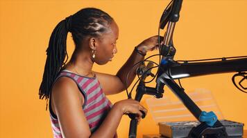Engineer uses screwdriver to tighten brake levers screws on bicycle handlebars, examining components, studio background. Expert unscrewing defective bike parts in order to recondition them, studio A photo