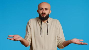 Middle eastern guy showing i dont know gesture in studio, being clueless and uncertain about answer to the question. Arab person doing confusion sign, shrugging and feeling unsure. Camera 2. photo
