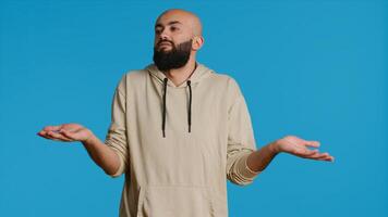 Middle eastern guy showing i dont know gesture in studio, being clueless and uncertain about answer to the question. Arab person doing confusion sign, shrugging and feeling unsure. Camera 1. photo
