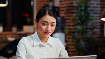 Zoom in on smiling businesswoman inputting financial data on laptop and analyzing sales report to plan business development. Close up of worker in office using device to do project research, camera B photo