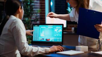 Manager and company financial advisor analyzing statistical graphs, zoom in shot on laptop screen. Management executive and worker comparing business revenue numbers in brick wall office, camera B photo