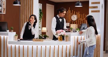 Employee looking at passport info for guest identification, undergoing check in process at front desk. Receptionist does tourist id verification and providing great concierge services for her. photo